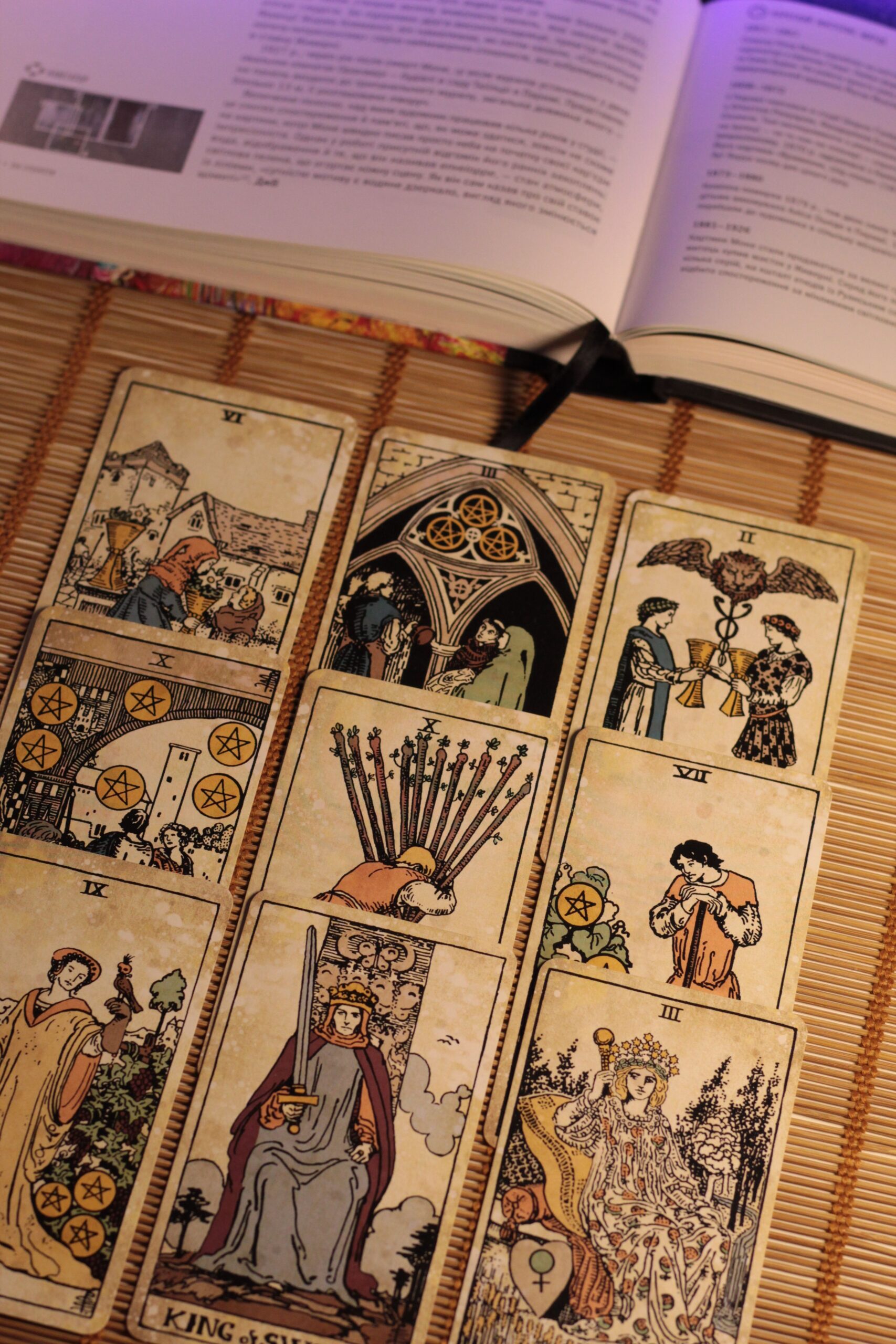 Cartas de tarô e livro aberto ilustram quanto custa imprimir um baralho personalizado